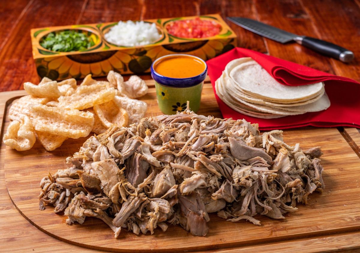 Barra de carnitas con tortillas, salsas y chicharrón